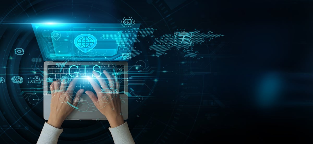 A man using a laptop with GIS on the keyboard analyzes and develops various information about spatial data mapping